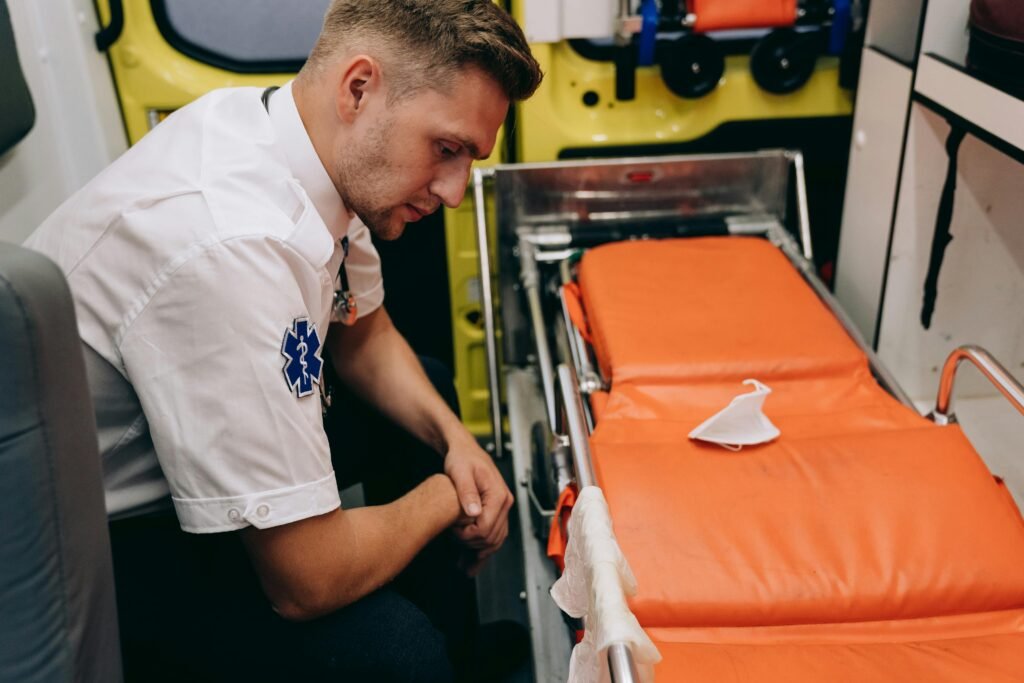 A paramedic prepares a stretcher inside an ambulance, focusing on readiness and professionalism.